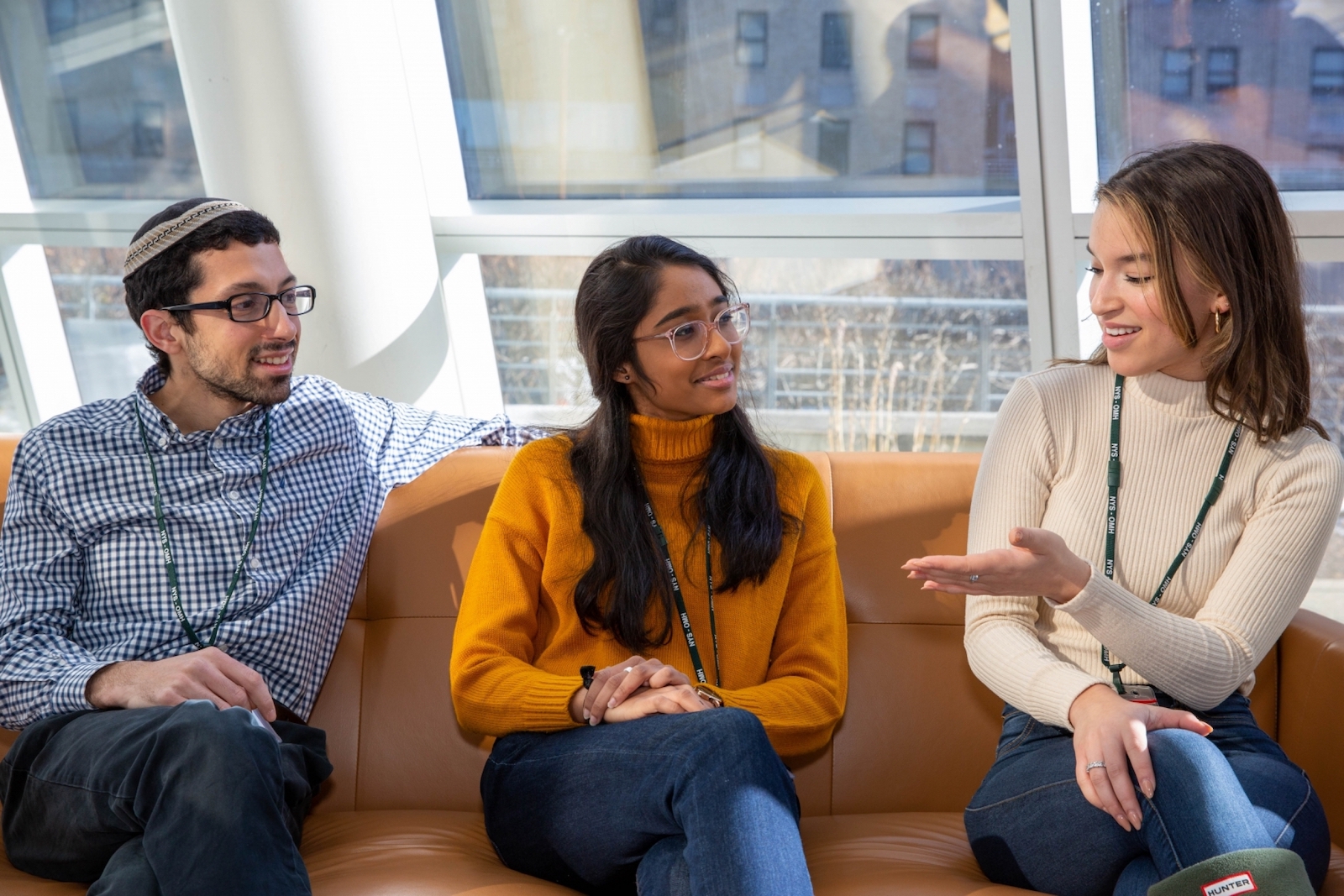 Three young adults sitting on a sofa conversing