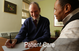 One older man smiling and showing a male patient text on a paper