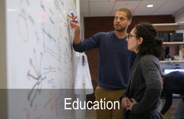 Man and woman standing looking at a whiteboard with writing on it