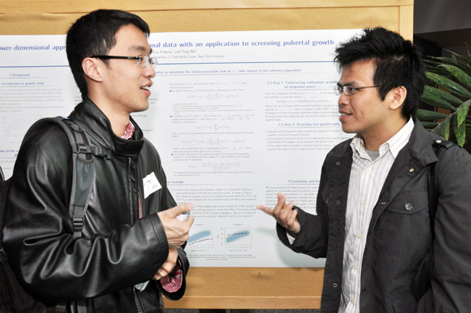 Two students talk in front of a poster presentation. 